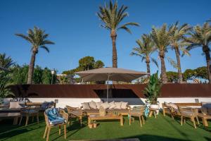 patio ze stołami, krzesłami i palmami w obiekcie Alidreams Carmen Beach Apartamentos w mieście El Campello