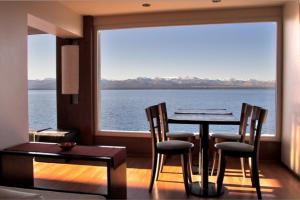 een eetkamer met een tafel en stoelen en een groot raam bij Hotel Bariloche Flat in Bariloche