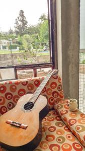 a guitar sitting on a couch next to a window at Hostel Casa de artistas Multiespacio Tanti in Tanti