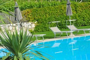 two chairs and two umbrellas next to a swimming pool at Gasthof Mondschein in Caldaro