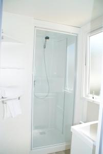 Baño blanco con ducha con puerta de cristal en Camping Montana Parc - Gassin Golfe de St Tropez - Maeva, en Gassin