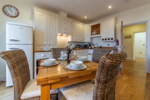 a kitchen with a wooden table with chairs and a refrigerator at 5 Fernhill in Carbis Bay