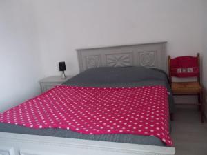 um quarto com uma cama com uma colcha rosa em Ti va zud em Plouguerneau
