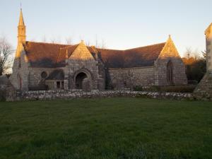 uma velha igreja de pedra com um campo de relva à frente em Ti va zud em Plouguerneau