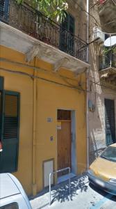 żółty budynek z drewnianymi drzwiami na ulicy w obiekcie Monfenera Apartment 2 w mieście Palermo
