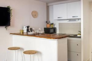 a kitchen with white cabinets and a counter with stools at Appartement chaleureux en centre-ville de Caen in Caen