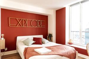 a bedroom with a bed with a red accent wall at Appartement chaleureux en centre-ville de Caen in Caen
