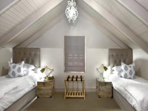 a attic bedroom with two beds and a chandelier at Mont d'Or Franschhoek in Franschhoek
