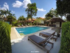a swimming pool with two chaise lounges next to a house at Dorm of Happiness by Tharaburi Resort in Sukhothai