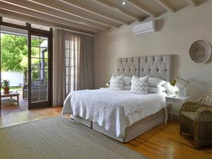a bedroom with a large white bed and a patio at Mont d'Or Franschhoek in Franschhoek