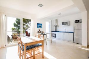 a kitchen with white cabinets and a table and chairs at Mestral in Port de Soller