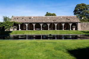 a stone building with a pond in front of it at Whatley Manor in Malmesbury