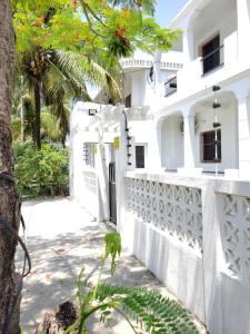 ein weißes Haus mit einem weißen Zaun und einem Baum in der Unterkunft SATRANA HOTEL TAMATAVE in Toamasina