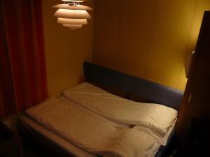 
a bed in a room with a lamp on the wall at Dovre Motel in Dovre
