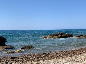 una spiaggia rocciosa con rocce in acqua di Paradise studios a Panormos