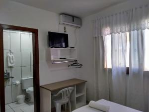 a room with a bathroom with a toilet and a television at Pousada Don João in Bento Gonçalves