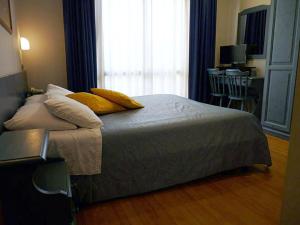 sypialnia z łóżkiem z żółtymi poduszkami i oknem w obiekcie Albergo Ristorante Cavallo Bianco w mieście Dronero