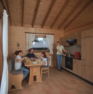 a group of people sitting at a table in a kitchen at Haus 2 - Typ B (Blockhaus) in Schönecken