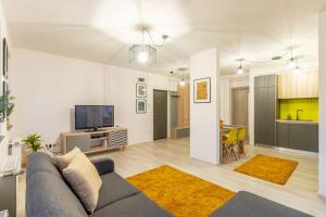 a living room with a couch and a tv and a kitchen at Modern and Stylish Apartment w Terrace in Cluj-Napoca