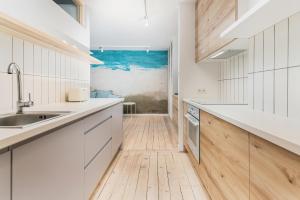 a kitchen with white cabinets and a wooden floor at Seaside Apartment Kraszewskiego by the Beach in Sopot by Renters in Sopot