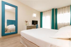 a bedroom with a large white bed and a mirror at Hotel Castilla Alicante in Alicante