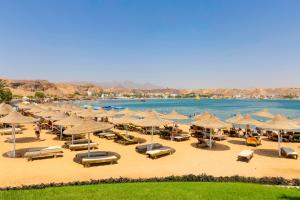 Xperience Golden Sandy Beach في شرم الشيخ: شاطئ فيه مظلات وكراسي وماء