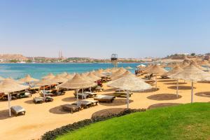 Xperience Golden Sandy Beach في شرم الشيخ: مجموعة من المظلات والكراسي على الشاطئ