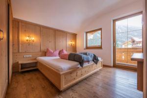 Schlafzimmer mit einem großen Holzbett und einem Fenster in der Unterkunft Alpenchalet Vital in Neustift im Stubaital