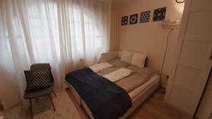 ein kleines Schlafzimmer mit einem Bett und einem Stuhl in der Unterkunft MHC Stúdió in Kaposvár
