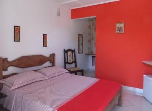 una camera da letto con un letto con una parete rossa di Maison Aires Malcher a Maricá