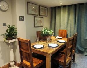 a wooden dining room table with chairs and a clock at Pili Pala Cottage, outstanding views and minutes to Zip World in Tregarth