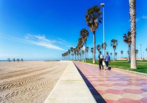 zwei Leute gehen einen Bürgersteig entlang am Strand in der Unterkunft Precioso piso en Roquetas de Mar in Roquetas de Mar