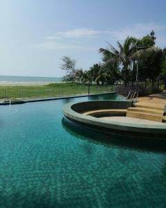 - une piscine d'eau bleue en face de la plage dans l'établissement Timurbay Seafront Residence aRRayyan Suites, à Kuantan