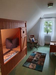 a bedroom with a bunk bed with a chair and a window at Dat moi lüttje Ostfreesen Landhuus in Halbemond