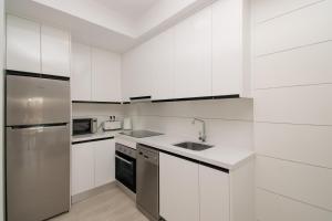 a kitchen with white cabinets and a stainless steel refrigerator at 58 Luxury Sunny Vacations in La Mata