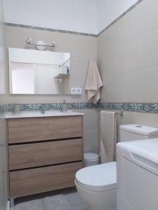 a bathroom with a toilet and a sink and a mirror at Dream House in Caleta De Fuste