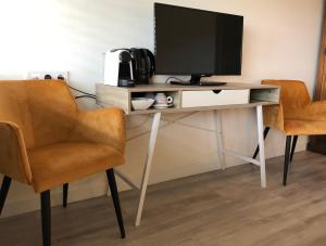 a desk with a tv and two chairs at Strandhotel Om de Noord in Schiermonnikoog