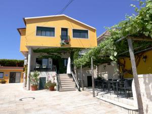 una casa amarilla con escaleras, mesas y vides en Pensión O Escondidino, en Baiona