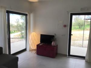 a living room with a tv and a couch and sliding doors at Monte Oliva - Turismo Rural in Cerro da Zorra