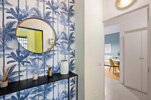 corridoio con specchio su una parete con carta da parati a palma blu di Gorgeous flat in the Design District a Milano