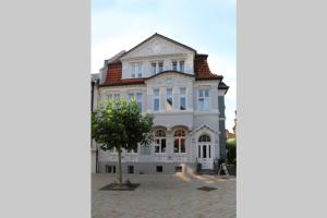 una gran casa blanca con un árbol delante en Villa Greve - Maisonette Suite en Bad Salzuflen