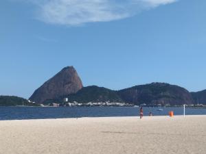 a person walking on a beach with mountains in the background at Lapa Casa Hostel in Rio de Janeiro