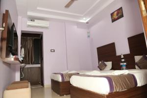 a hotel room with two beds and a television at Hotel Sai Guest House in Nagpur