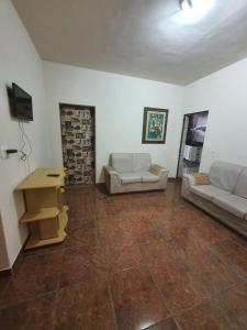 una sala de estar con 2 sofás blancos y una mesa. en Hostel Jussa en Belo Horizonte