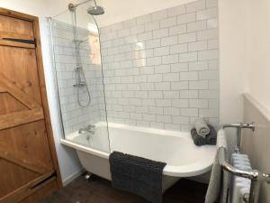 a white bathroom with a tub and a shower at Gellibant Cottage in Llanbedr