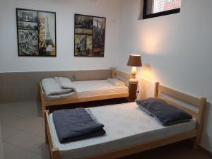 two beds in a room with a lamp and pictures on the wall at North Mitrovica Center in Mitrovicë