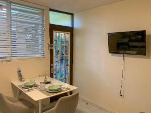 a dining room with a table and a television on the wall at Cute Apartment with Patio and Laundry Pet Friendly in Ponce