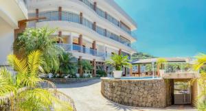 um grande edifício com palmeiras na frente em Hospedaria Vitória Mar em Ubatuba