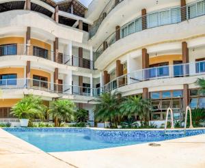 an apartment building with a swimming pool and palm trees at Hospedaria Vitória Mar in Ubatuba