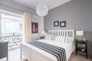 a white bedroom with a bed and a balcony at Kleio by Heloni Apartments in Athens